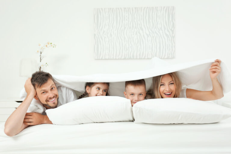 Family lying on bed in hotel room protected by a Mattress Safe mattress encasement